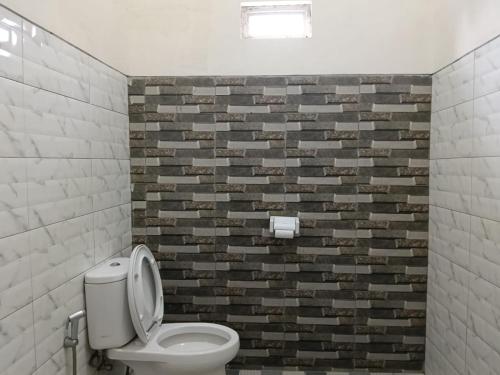 a bathroom with a toilet and a brick wall at Savana Guesthouse in Bromo