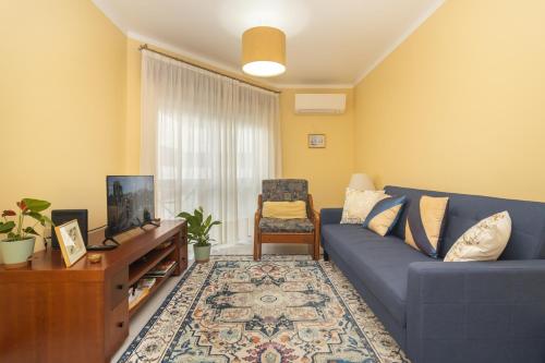 セトゥーバルにあるCoast 2 Bedroom Apart Setúbal 45 min from Lisbonの青いソファとテレビのあるリビングルーム