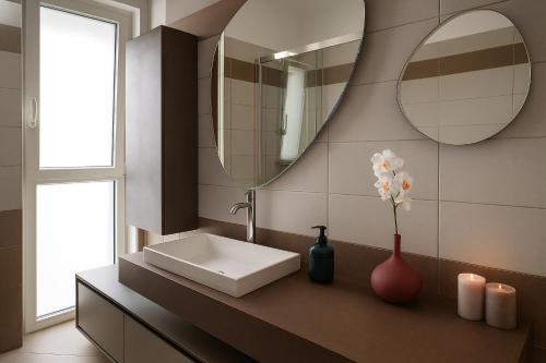 a bathroom with a sink and a mirror and a vase with flowers at Oceanomare Beach Home in Bari