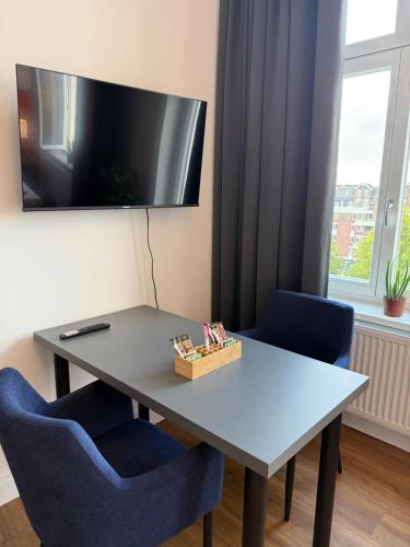 a table with two blue chairs and a television on the wall at 181 City View Hamburg in Hamburg