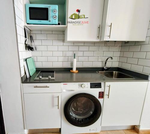 a small kitchen with a washing machine and a microwave at Casa Gala in Corralejo
