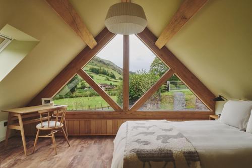 a bedroom with a large window with a bed and a desk at Hay Barn in Trefeglwys
