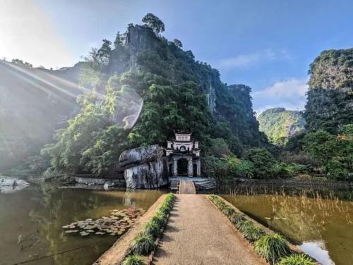 a bridge over a river with a building on a mountain at An Homestay Tam Coc in Ninh Binh