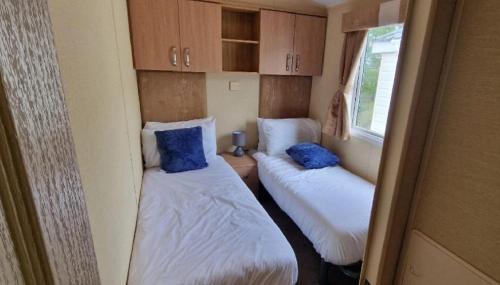 Una pequeña habitación con dos camas y una ventana. en Lovely 8 Berth Caravan With Large Decking At Withernsea Sands Ref 79005Kg, en Waxholme