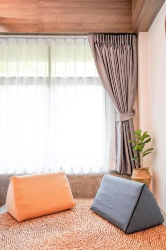 a bed with an orange pillow in front of a window at Krung Boutique Hotel in Bangkok