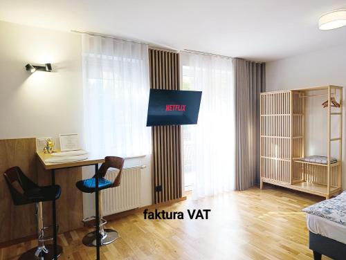 a room with a tv and a desk and a bed at Kolory Warmii Apartamenty Biały i Szary in Olsztyn