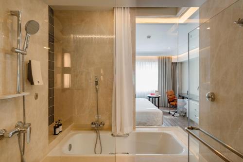 a bathroom with a bath tub and a bedroom at Ramada Plaza by Wyndham Bangkok Menam Riverside in Bangkok