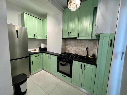 eine grüne Küche mit grünen Schränken und einem Kühlschrank in der Unterkunft Studio One Cassas Residence in Craiova
