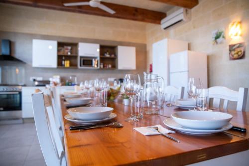 a long wooden table with plates and glasses on it at Ta' Ganna Farmhouse in Sannat