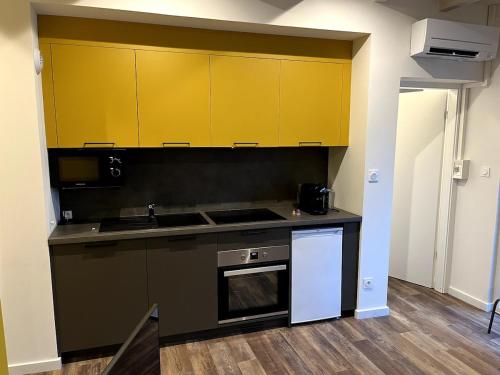 a kitchen with yellow cabinets and a stove at Appartement 9 lumineux, agréable in Ohnenheim