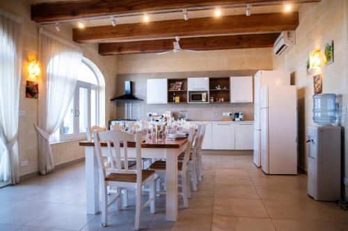 a kitchen with a table with chairs and white appliances at Ta' Giga Farmhouse in Sannat