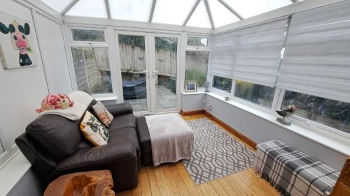 a living room with a leather couch and windows at Warm and Cosy 1 bed house in Chipping Norton in Chipping Norton