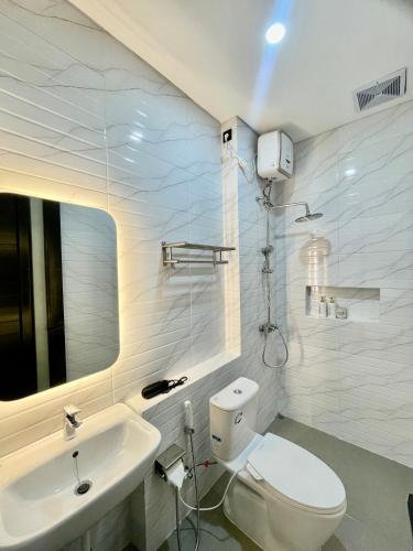 a white bathroom with a toilet and a sink at Tutur Bali Guest House in Ungasan