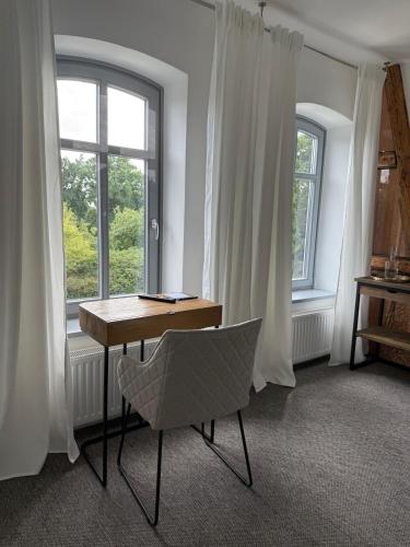 a table and a chair in a room with windows at Edelhof1877 in Thedinghausen