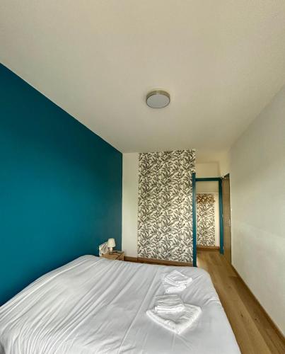a bedroom with a bed with a blue wall at Happy Break in Saint-Michel-en-lʼHerm