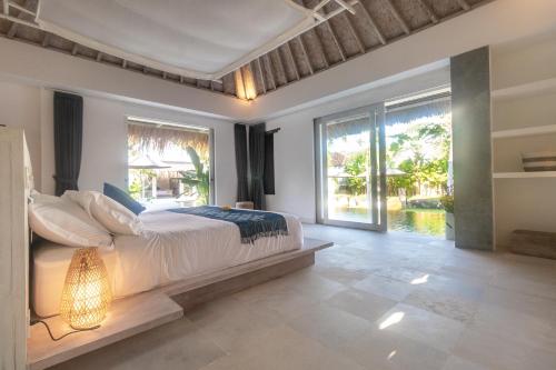 a bedroom with a large bed and large windows at OMAÏA Private villas in Amed