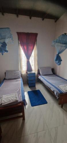 two beds in a room with a window at Perivale Budget Stay in Moratuwa