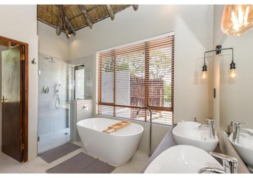 a bathroom with two sinks and a tub and a bath tub at Mziki Safari Lodge in Vaalkop Dam