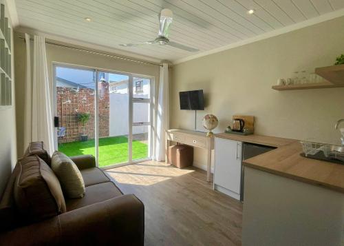 sala de estar con sofá y cocina con ventana en Mossel Bay Self Catering - Near Bayview Centre & Hospital, en Mossel Bay