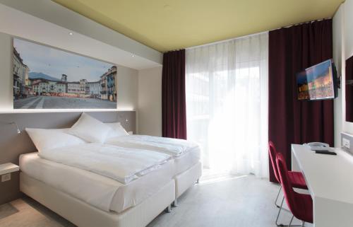 a hotel room with a bed, chair and a window at Hotel City Locarno in Locarno