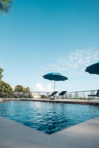 a pool with chairs and umbrellas next to the water at Les Ti Kaz d'Auguste in Les Avirons