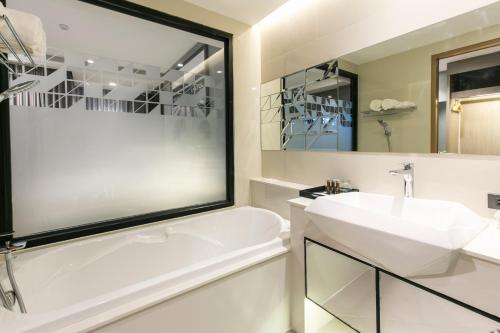a bathroom with a white tub and a sink at The Crystal Hotel Buriram - formerly X2 Vibe Buriram in Buriram