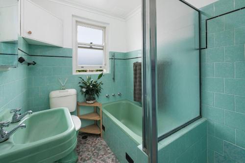 a bathroom with a green tub and a sink at North Facing Seaside Apartment in Cronulla
