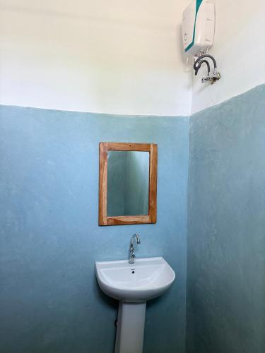 a bathroom with a sink and a mirror on the wall at Zanzi coconut house in Jambiani