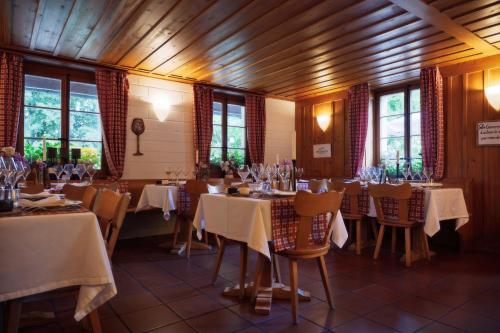 a dining room with tables and chairs and windows at La Hohmatt in Tüscherz-Alfermée