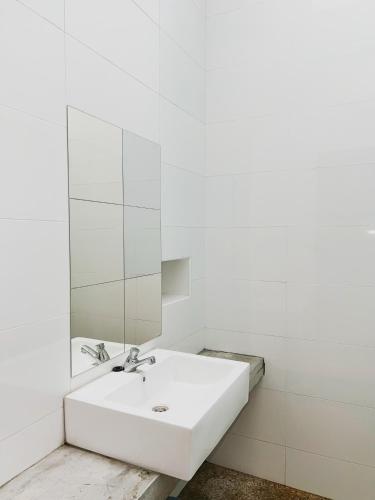 a white bathroom with a sink and a mirror at Cozy Private Room for Relaxing Stays in Nibung Tebal