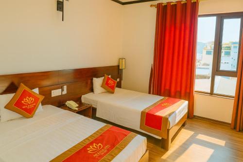 Una habitación de hotel con dos camas y una ventana. en Sen Hotel Hạ Long, en Ha Long