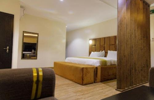 a bedroom with a large bed with a wooden headboard at Vizit Hotel & Suites in Benin City