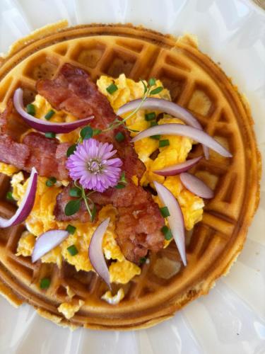 a waffle with bacon and a flower on top at Sunrise Brunch & Stay in Pai