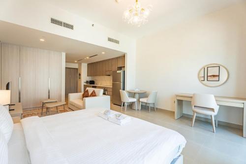 ein Schlafzimmer mit einem weißen Bett und ein Esszimmer in der Unterkunft F1 Lovers Escape Yas Golf Studio Near Yas Marina Circuit in Abu Dhabi