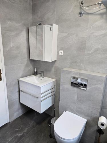 a bathroom with a white sink and a toilet at Apartman Bugi Vukovar in Vukovar
