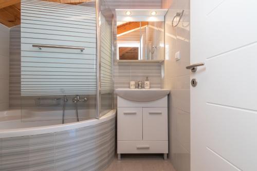 ein Badezimmer mit Waschbecken, Dusche und Badewanne in der Unterkunft Demargia Villa A - Loft Apartment in Áno Yerakaríon