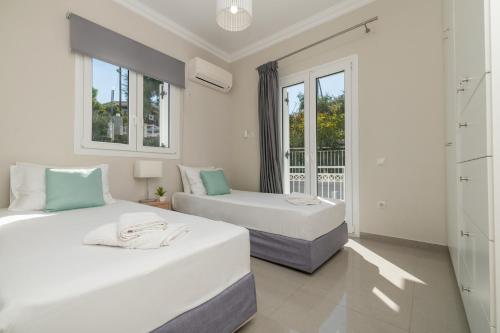 two beds in a room with two windows at Demargia Villa A - First Floor Apartment in Áno Yerakaríon