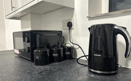 eine Küchentheke mit Kaffeemaschine und Mikrowelle in der Unterkunft New Medway Private Double room with private bathroom close to hospital and station in Gillingham