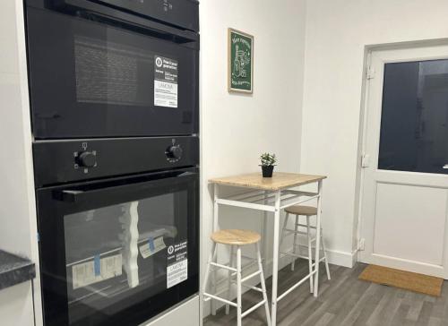 eine Küche mit einem schwarzen Ofen und einem kleinen Tisch in der Unterkunft New Medway Private Double room with private bathroom close to hospital and station in Gillingham
