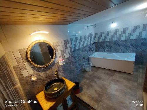 une salle de bain avec un lavabo, une baignoire et un miroir dans l'établissement Alcove Resort Vagator, à Vagator