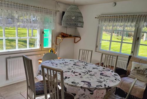 ein Esszimmer mit Tisch und Stühlen und Fenstern in der Unterkunft Three cozy cottages, sauna and hot tub in Lohja