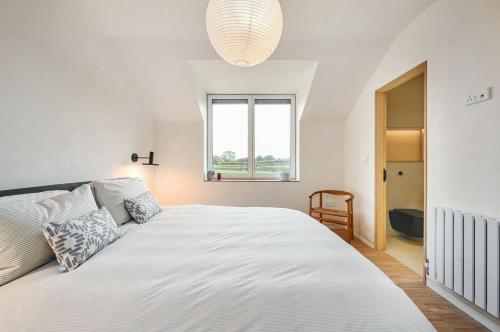 a white bedroom with a large bed and a window at Brook Lodge Farm in Isfield