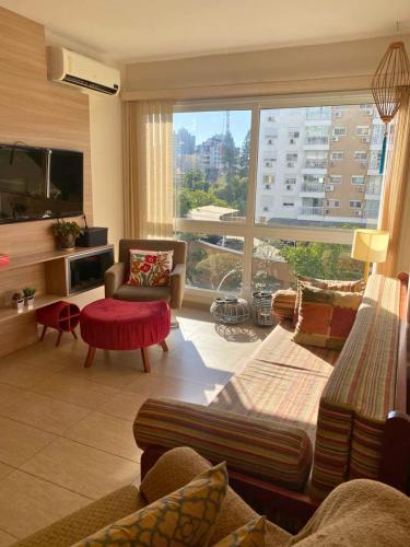 a living room filled with furniture and a large window at Ótimo AP 2 Dorm com suíte prox ao Consulado Americano in Porto Alegre