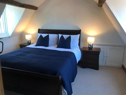 a bedroom with a large bed with blue sheets and pillows at Cottage by the Castle grade II in Kenilworth