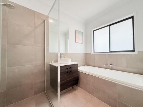 ein Badezimmer mit Badewanne, Waschbecken und Dusche in der Unterkunft Spacious Family Home 4B2B in Browns Plains in Browns Plains