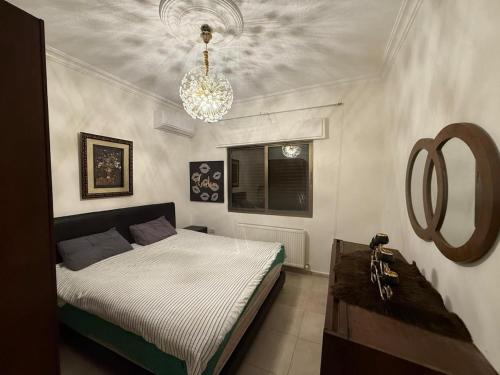 Un dormitorio con una cama y una lámpara de araña. en Furnished luxuries Apartment with a Stunning View, en Amán