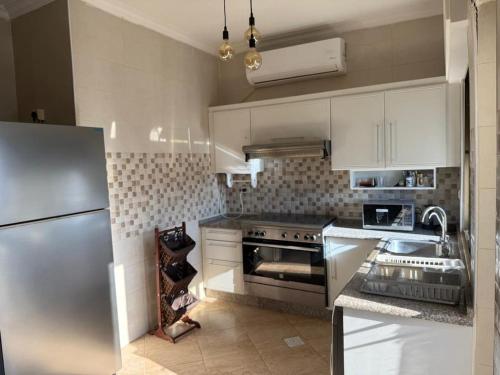 Una cocina con gabinetes blancos y un refrigerador de acero inoxidable. en Furnished luxuries Apartment with a Stunning View, en Amán