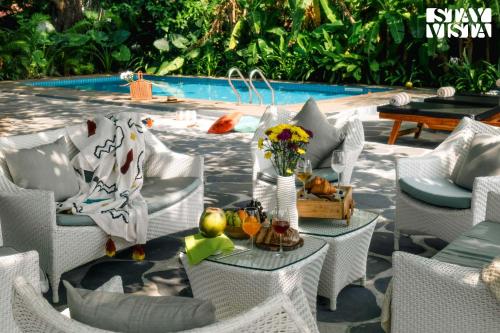 Un patio con sillas y una mesa con una bandeja de frutas. en StayVista at Di Mora by the Sea with Lawn & Pool, en Baga