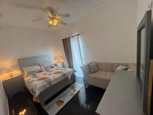 een slaapkamer met een bed en een bank bij Modern 3-Bedroom Apartment with Pool in Boca Chica