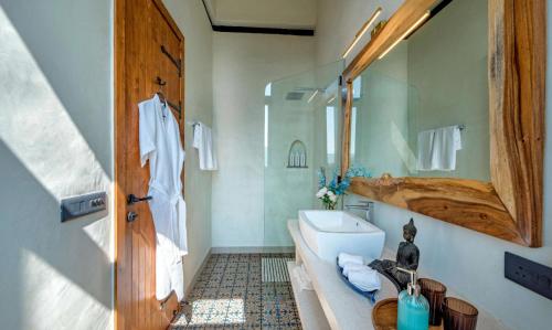 um banheiro com banheira, pia e espelho em SaffronStays Satori Perch Regal - 4BR Tuscan-style villa with pool, farm meals & 270 Degree Mulshi Lake views near Pune em Mulshi